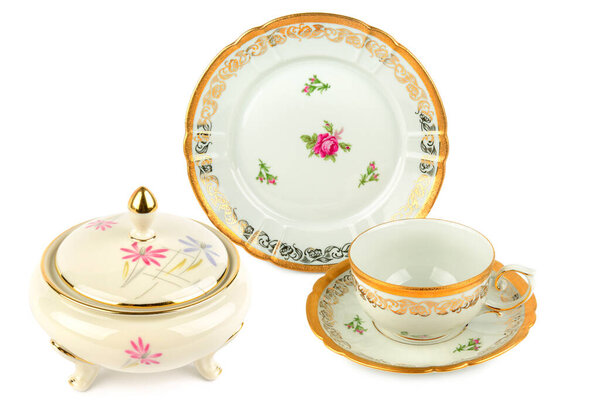 An elegant porcelain tea set, including a sugar bowl, cup, and plate, features intricate floral patterns and classic gold trim. This studio-shot image is perfect for themes of luxury, hospitality, and traditional tableware, with copy space.