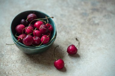 Yeşil seramik kasede organik kirazlar ahşap arka planda, yakın plan, makro fotoğraf.