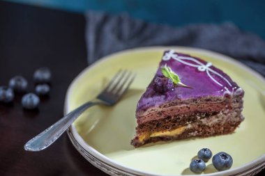Siyah ahşap arka planda klasik çatalı olan lezzetli yaban mersinli pasta, yakın plan, makro fotoğraf, natürmort.