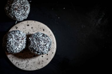 Siyah arka plan üzerine hindistan cevizi serpiştirilmiş çikolatalı trüf mantarları, izole edilmiş makro fotoğrafçılık.