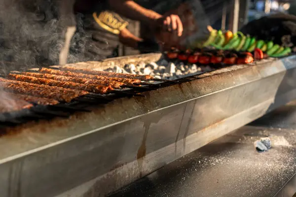 Adana kebabı barbeküde biber ve domatesle ızgara yapıyor.