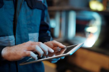 Hands of contemporary engineer of industrial plant with tablet pointing at screen or scrolling through internet resources for data