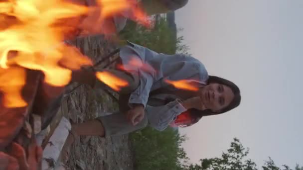 Vertical Young Dark Haired Biracial Woman Sitting Lakeshore Watching Campfire — Stock Video