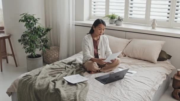 Wide Portrait Young Asian Female Freelancer Holding Papers Sitting Bed — Stockvideo