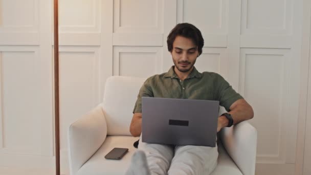 Medium Long Young Middle Eastern Man Sitting Armchair Home Typing — Vídeo de stock