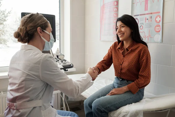 Female Clinician Shaking Hand Young Happy Hispanic Patient Sitting Couch — Stockfoto