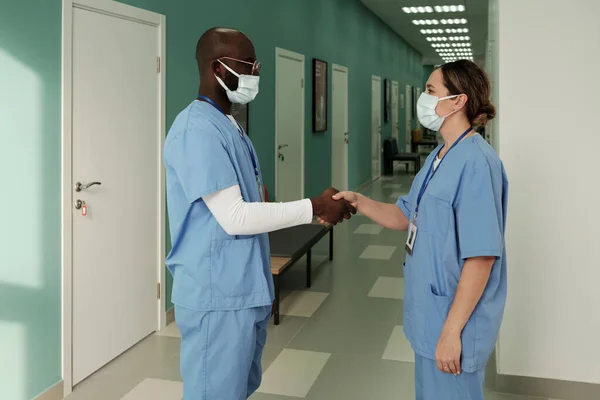 Two Young Successful Interracial General Practitioners Medical Scrubs Handshaking Corridor — Stock Photo, Image