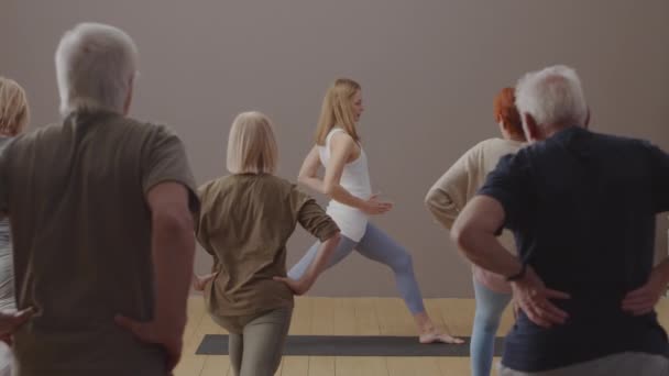 Blonde Female Instructor Teaching Yoga Senior Men Women Showing Correct — Stockvideo