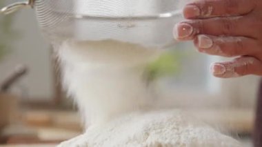 Close up shot of female hands sifting wheat flour for baking