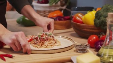 Close up tracking shot of female hands putting plate with homemade spaghetti bolognese on kitchen table