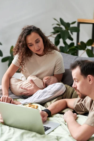 Young Female Baby Her Husband Sitting Double Bed Choosing New — Stockfoto