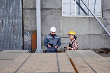 Two workers of distribution warehouse checking barcodes on containers with new spare parts for contemporary industrial machines