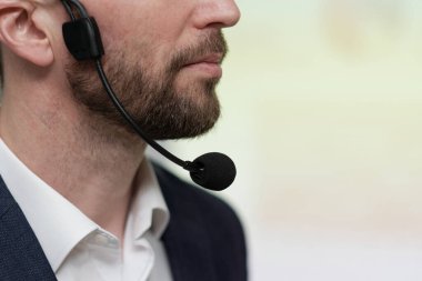 Close-up of lower part of face of young serious businessman with microphone under his chin against white background
