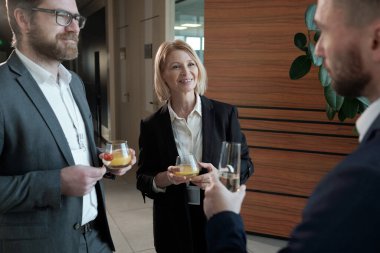 Group of contemporary entrepreneurs with juice looking at colleague with flute of champagne making toast for business at buffet