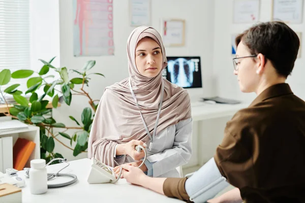 Young Serious Muslim Doctor Measuring Blood Pressure Sick Female Patient — Stock Photo, Image