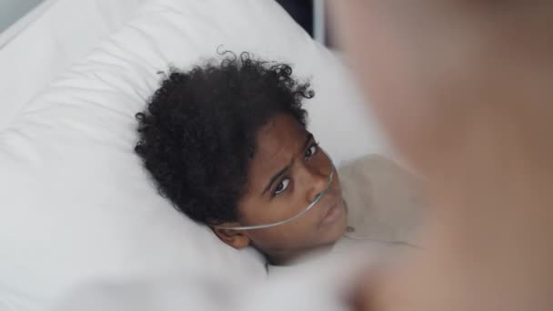Через Плечо Обрезанный Доктор Разговаривает Афроамериканским Мальчиком Кислородной Трубкой Лежащей — стоковое видео