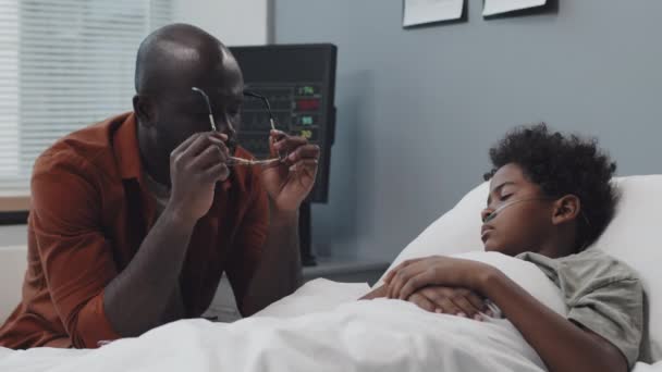 Medium Young Devastated African American Man Sitting Bed Unconscious Boy — Vídeo de Stock