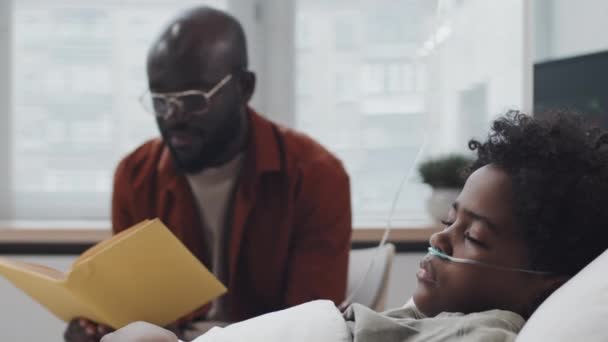 Baixo Ângulo Homem Negro Desfocado Lendo Livro Para Filho Inconsciente — Vídeo de Stock