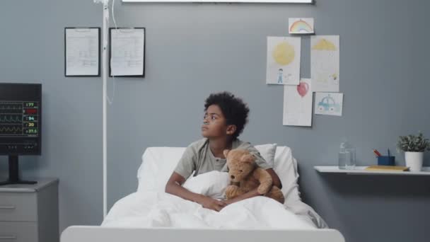 Medium Positive Adorable Black Boy Sitting Stuffed Bear Hospital Bed — Stok video