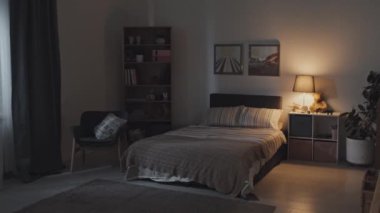 Geceleri yatak, sandalye, raflar, tablolar ve gece lambasının açık olduğu odayı izliyoruz.