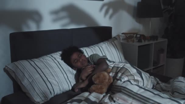 Közepes Kilenc Éves Fekete Fiú Ölelgeti Játékmacit Otthon Alszik Sötétben — Stock videók