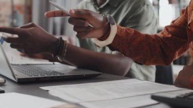Midsection of hands of cropped couple sitting at desk indoors in afternoon, using portable computer