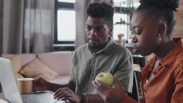 기사보기 아프리카 아프리카 미국인 사과를 즐기고 있으며 아파트에서 책상에 컴퓨터를 — 비디오