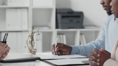 Midsection of cropped woman and man sitting at desk in office, having business meeting with unrecognizable lawyer at daytime, signing contract, shaking hands