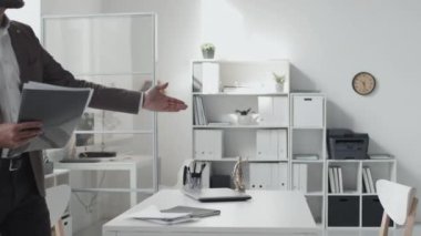 Side-view of blue-eyed Caucasian male lawyer and young Black married couple walking in white office, sitting at desk, having business conversation at daytime