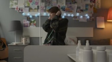 Selective focus of various pill jars in foreground of young Caucasian female adult with nasal cannula sitting on bed in decorated hospital ward