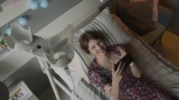 病院病棟のベッドに横になってスマートフォンでビデオ通話 笑顔と話しています — ストック動画