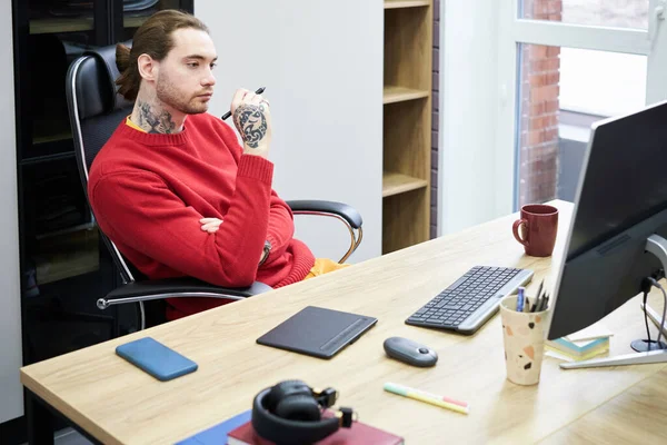 Young Graphic Designer Sitting Desk Looking Computer Monitor Pensive Expression — Zdjęcie stockowe