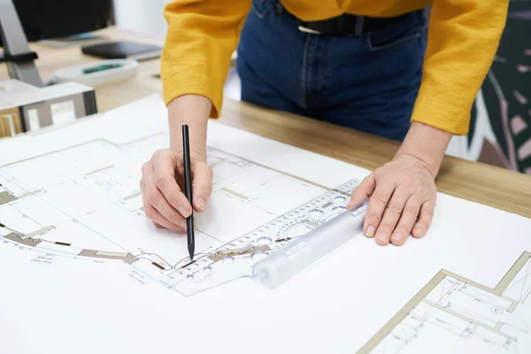 Stock image Close-up of architect using pencil and ruler to draw blueprint on table at office