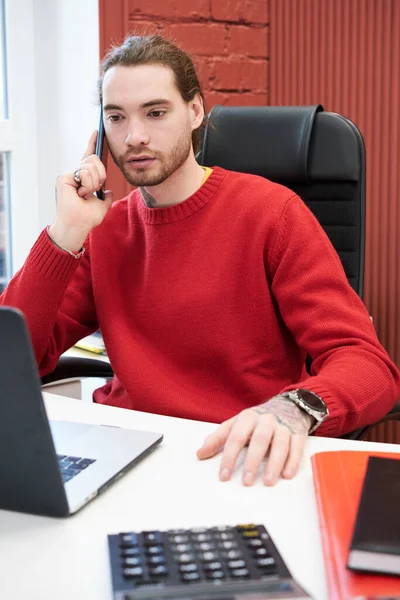 Young Businessman Sitting His Workplace Laptoplooking Monitor Talking Mobile Phone — Zdjęcie stockowe