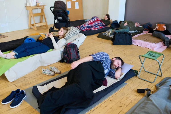 Junger Männlicher Flüchtling Schläft Auf Matratze Unter Decke Gegen Frau — Stockfoto