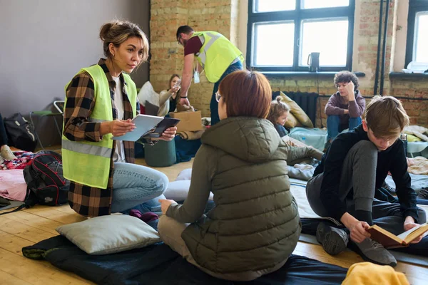 Female Volunteer Mobile Gadgets Communicating One Refugees While Sitting Squats — Stockfoto