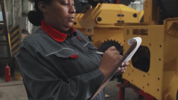 공장에서 모자를 제복을 공장을 점검하는 아프리카 근로자를 배치하는 클립보드에 필기를 — 비디오
