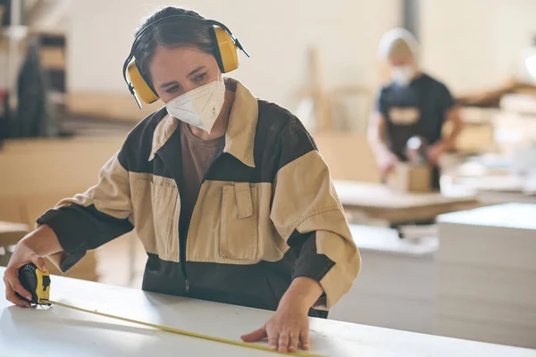 Young Female Worker Protective Mask Headphones Measuring Plank Tape Measure — Foto de Stock