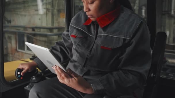 Tilting Black Woman Orange Hard Hat Work Overalls Sitting Cabin — Vídeos de Stock