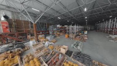 Drone tracking view of warehouse with heavy machinery parts in afternoon