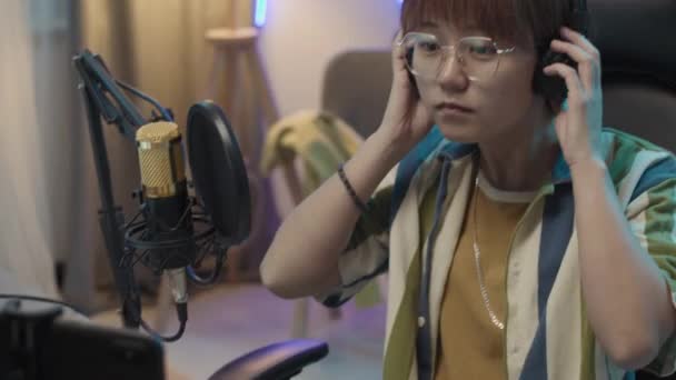 Střední Naklápění Záběr Mladé Asijské Ženy Brýlích Sluchátkách Zapínání Smartphone — Stock video