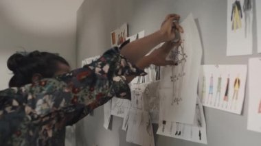 Erkek Hintli moda tasarımcısı diğer çizimler ve yaratıcı atölyede ilham verici fikirlerle duvara resim çiziyor.