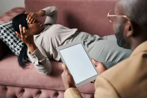 年轻的男性心理治疗师 带着平板电脑坐在女病人面前 放松地躺在沙发上 描述她的忧虑和问题 — 图库照片