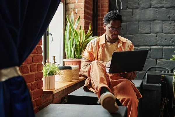 Young Black Man Casualwear Sitting Windowsill Green Domestic Plants Neworking — Stock Photo, Image