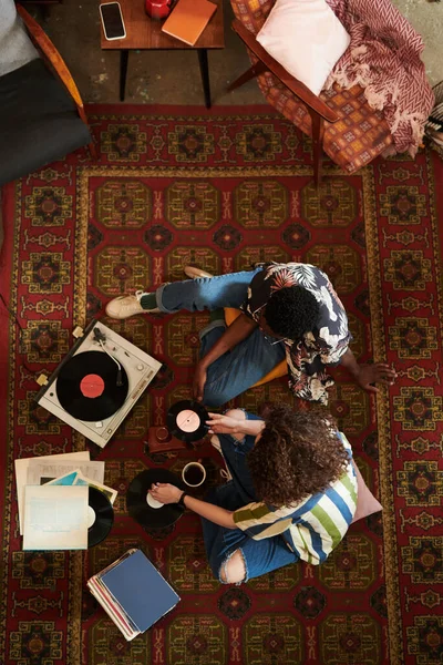 不同文化间的年轻夫妇穿着时髦的便服坐在客厅的红地毯上 听着录音机里的Vynone光盘 — 图库照片