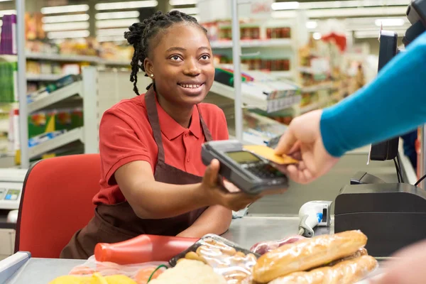 Joven Vendedor Sonriente Mirando Consumidor Sosteniendo Tarjeta Crédito Sobre Terminal — Foto de Stock