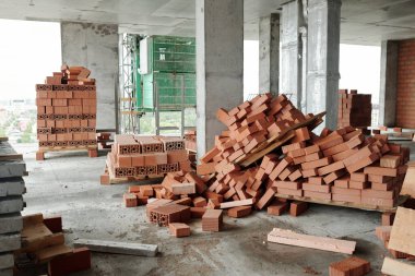 Beton kolonları, zeminde yeni tuğlalar ve diğer yapı malzemelerinin bulunduğu tamamlanmamış apartman bloklarının içi