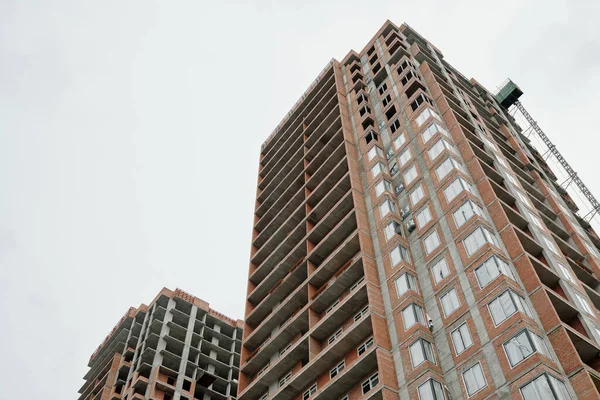 在现代城市的市中心 摩天大楼或高层公寓的未完工建筑在灰蒙蒙的天空下形成了一排公寓 — 图库照片