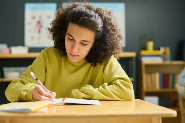 Male Teenager Yellow Pullover Making Notes His Copybook While Sitting — Stock Photo, Image
