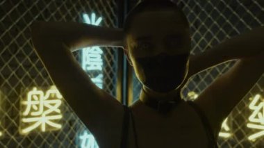 Kafası kazınmış, yüzü siyaha boyanmış, stüdyoda ellerini ve vücudunu hareket ettiren, hiyeroglifler şeklinde neon ışıkları olan, nirvana ve batı cenneti anlamına gelen bir kızın yakın çekimi.